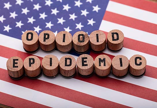 an American flag background of wooden blocks with opioid epidemic spelled out