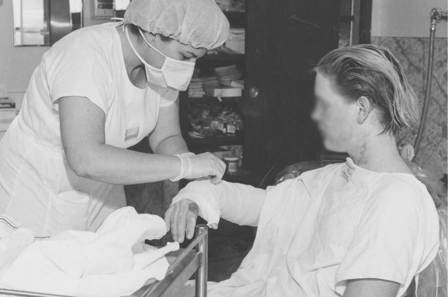 Nurse tends to bandaged arm of burn patient