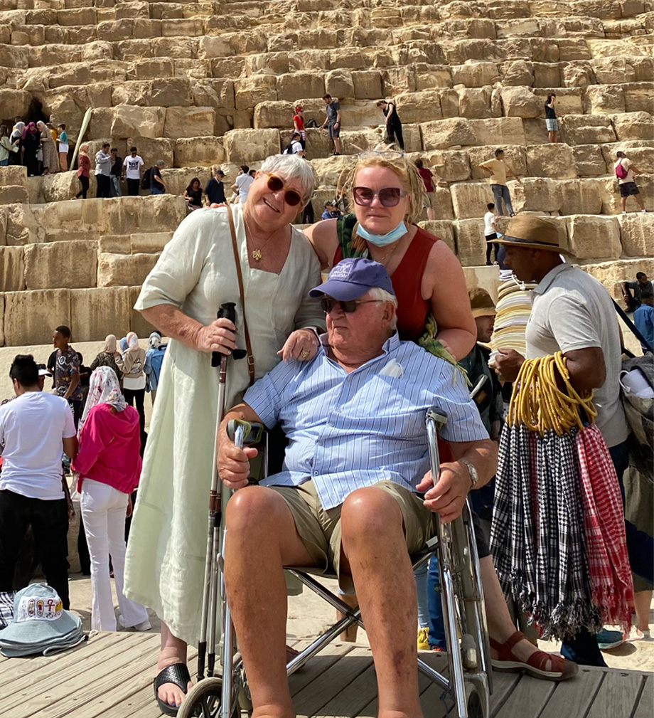 Gunilla Borgren stands next to her daughter while Hugo sits in wheelchair in front of Egyptian pyramids