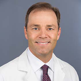 Dr. Joshua Fenton in a white doctor’s robe