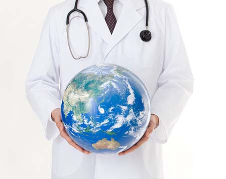 Doctor wearing white gown and stethoscope and holding globe in hands