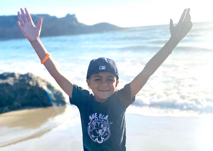 Isaac at the ocean with his hands up