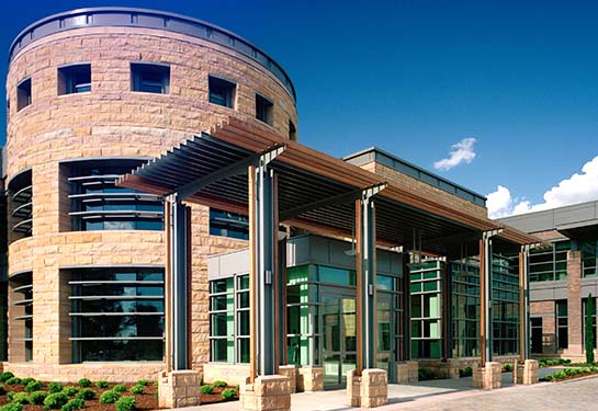 The exterior of the UC Davis MIND Institute, a large brown and glass building featuring a rotunda in the center. 