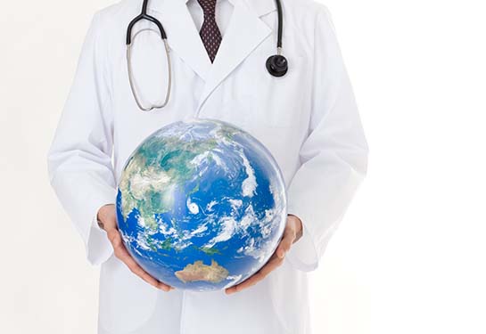 Doctor wearing white gown and stethoscope and holding globe in hands