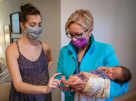 Diana Farmer holding Robbie with Emily looking on and pointing to her toes