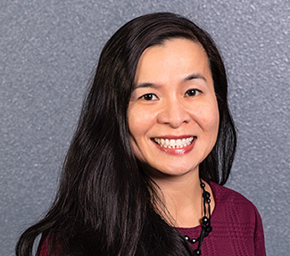 Asian woman with long black hair, wearing burgundy sweater on gray background.