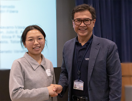 Cancer center director presenting first place poster presentation award to Menghuan Tang.