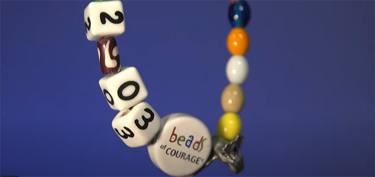 The prominent bead - a Bead of Courage - within a string of beads 