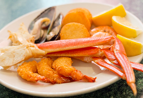 a plate with shrimps, crabs, mussels and lemon wedges