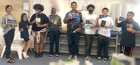 Sarah Nava and seven children standing and holding books in a classroom