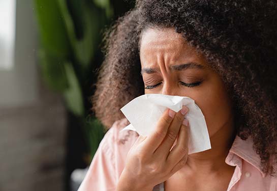 woman sneezing into a tissue