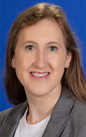 A smiling woman with light-brown hair wearing a grey business suit and white shirt 