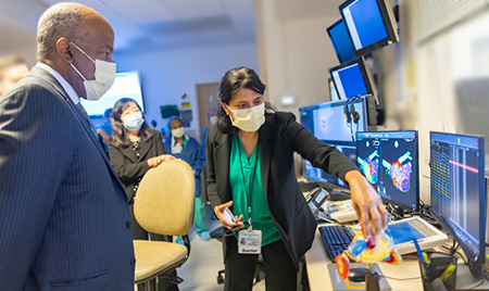 Group of individuals looking at digital heart on two computer screens