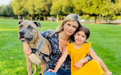 Brianna, Sophia and Tyson sitting on the grass with trees in the background