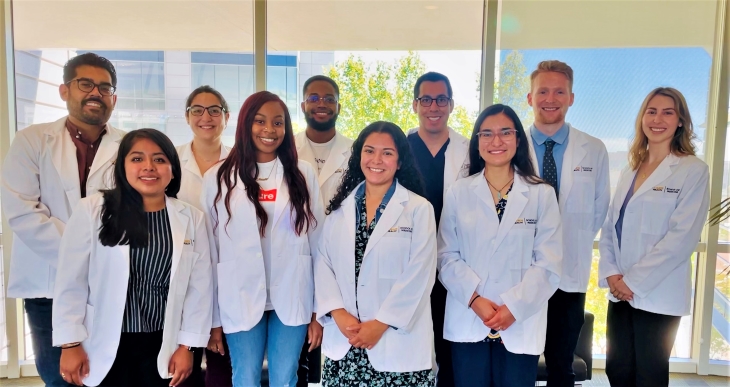 a group of 10 students standing in their white lab coats on their first day of medical school in 2021