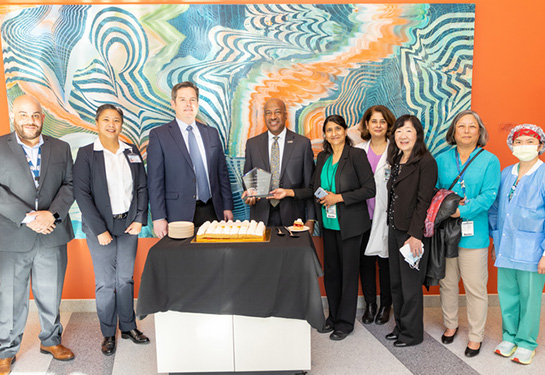 Group of people posing behind a cake