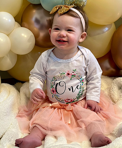 Adelyn wearing a white shirt sitting among balloons