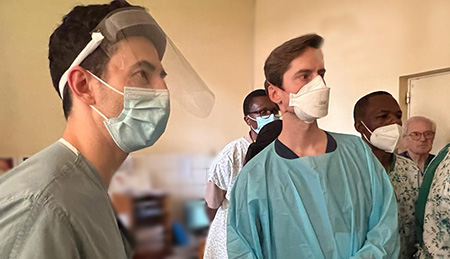Two doctors wearing scrubs and masks looking at a monitor