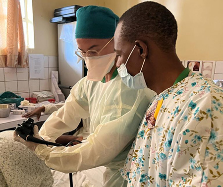 Sean Nguyen standing over a patient demonstrating a procedure to another doctor