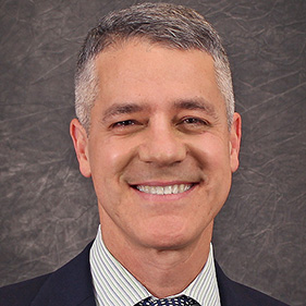 Middle aged man with black and grey hair smiling in portrait photo