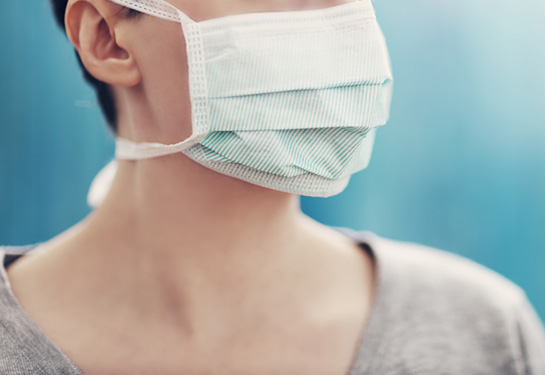 Woman wearing a grey sweater and mask over face