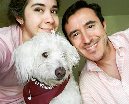 2.	Man with dark hair next to woman with dark hair and a white dog. 