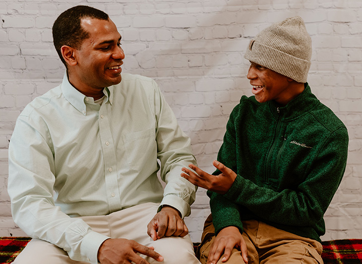 Darren and his dad, Baron sitting on a bench in front of a white brick wall