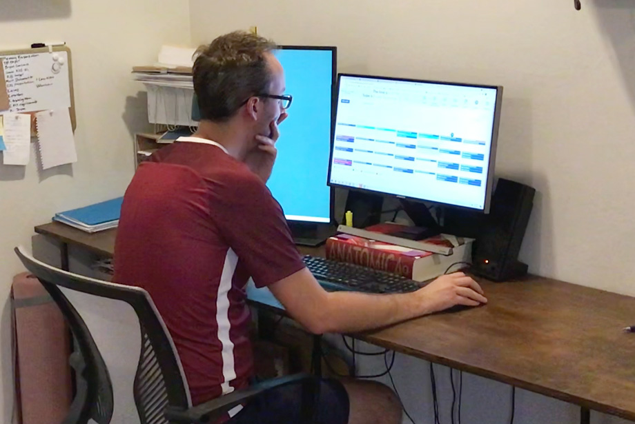 Man sitting at desk looking at calendar on computer screen