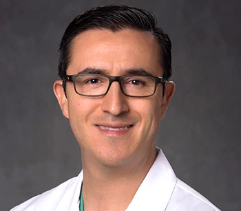 Man with dark hair, glasses and white lab coat.