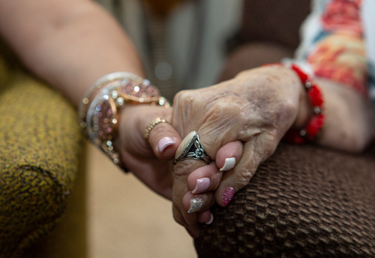Close up of older woman and younger woman holding hands