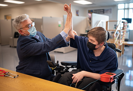 Dr. Craig McDonald holding the arm up of a patient with Duchenne muscular dystrophy