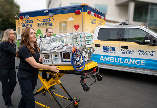 Two nurses pushing equipment with the UC Davis Children's Hospital ambulance in the background