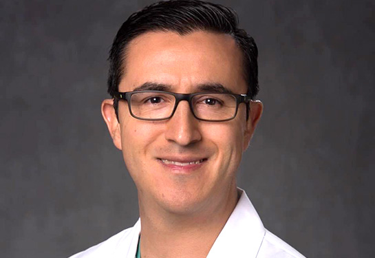 Man with dark hair, glasses and white lab coat.