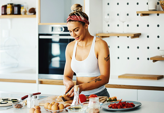 Young fit woman preparing meal in the kitchen.