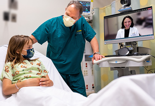 young male speaking with a doctor via telemedicine with a nurse in the room