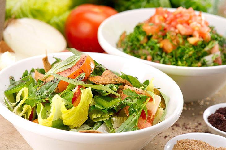 Plates of traditional salad and tabbouleh on a rustic background