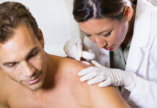 Dermatologist examining skin of a patient
