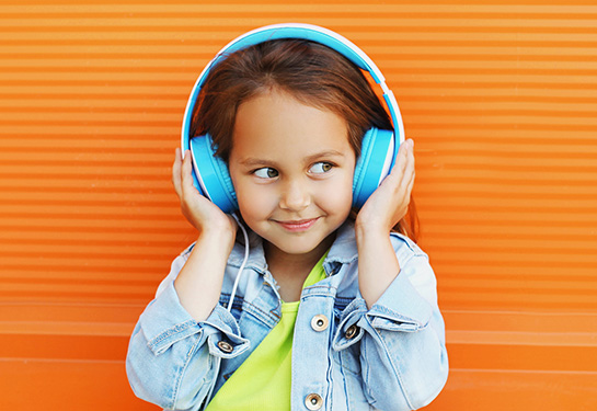 Smiling young girl wearing headphones listening to music