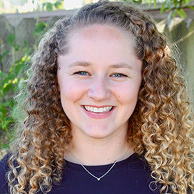 A smiling woman with curly blond hair in a formal headshot photo.