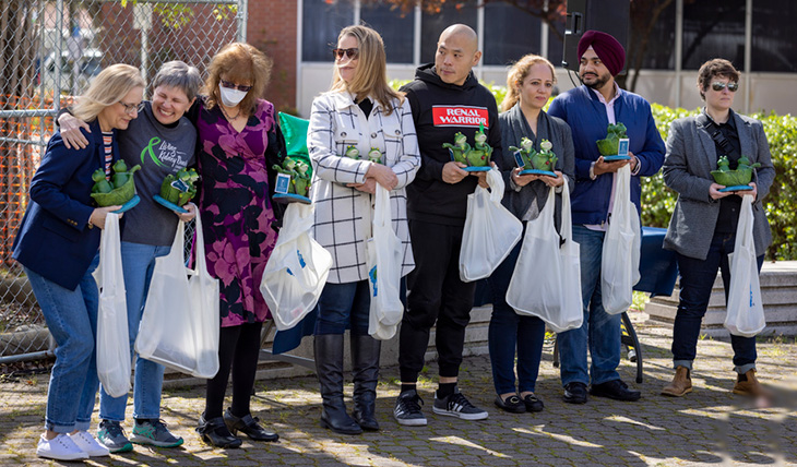 Eight people standing arm to arm and holding white bags