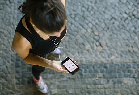 Top view shot of woman training outdoors and using a smartphone to monitor her fitness progress.