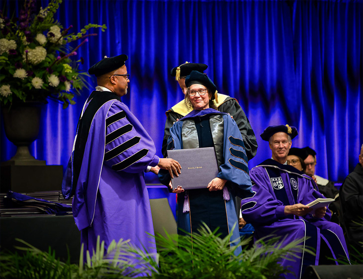 Piri Ackerman-Barger, right, shakes hand with Portland faculty member and receives bound degree