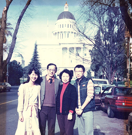 Asian American family with mother and father posed on the street and in center of photo with daughter to left and son to right of them.