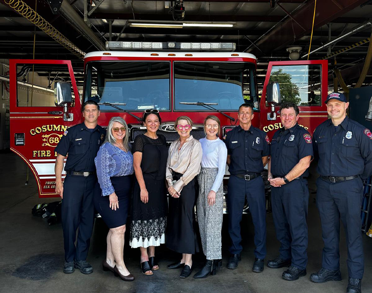 Group of people posed shoulder-to-shoulder standing in front of fire engine