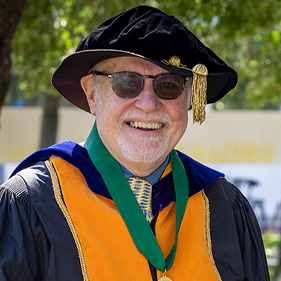 Dean Steven Cavanagh in cap and gown outside wearing sunglasses