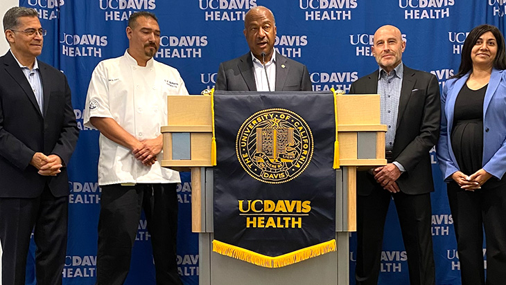 A group of people stand behind a podium, in front of a UC Davis Health backdrop