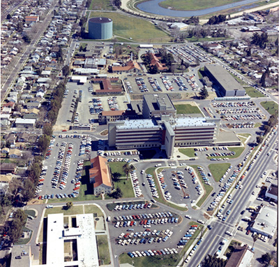 Aerial photo of hospital with parking lots and small buildings surrounding it.