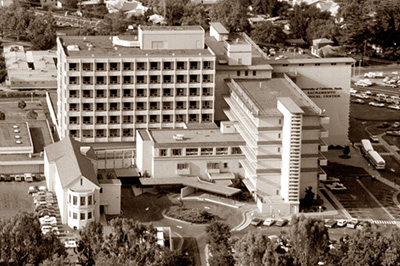 Black and white aerial photo of hospital with roundabout in front.
