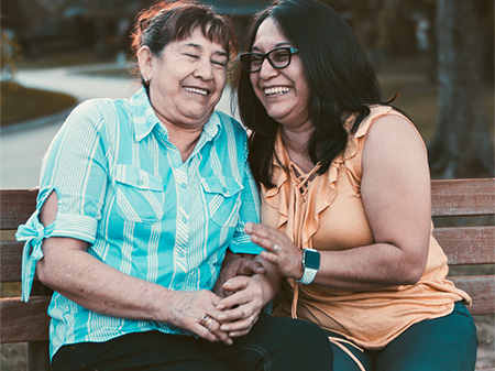 Two women sitting on a bench and laughing