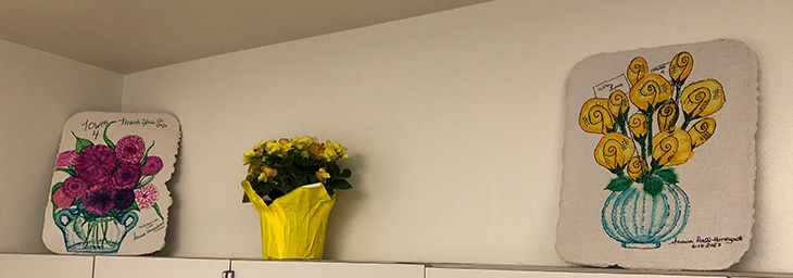 Two flower paintings sitting on top of shelves 